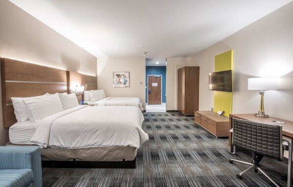 Quarto de hotel com duas camas, uma escrivaninha, uma cadeira, uma televisão e um abajur.