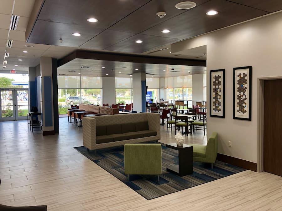 A spacious indoor area with a seating arrangement, including a sofa and chairs, and a large window providing a view of the outside.