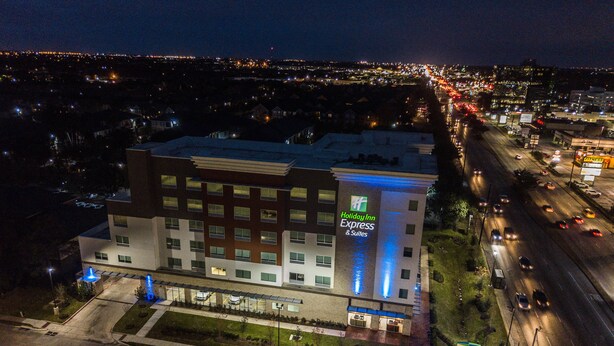 Edificio de Holiday Inn Express & Suites con diseño moderno, destacando un letrero llamativo y un frente bien iluminado.