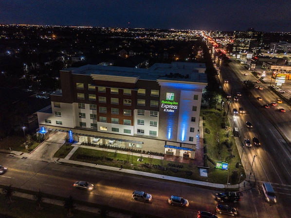 Edifício da Holiday Inn Express & Suites com design moderno, apresentando uma placa em destaque e fachada bem iluminada.