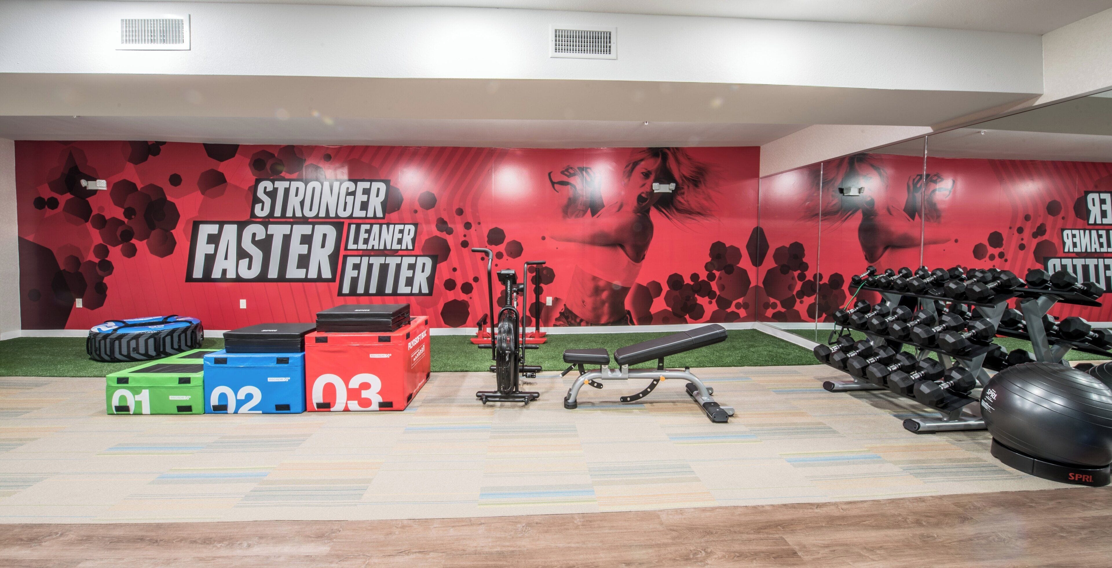 A gym with exercise equipment, a wall with motivational text, and numbered weightlifting boxes.
