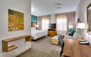 A hotel room with a bed, a desk, a chair, a TV, and a painting on the wall. - Staybridge Suites Gainesville I-75 by IHG (Gainesville)