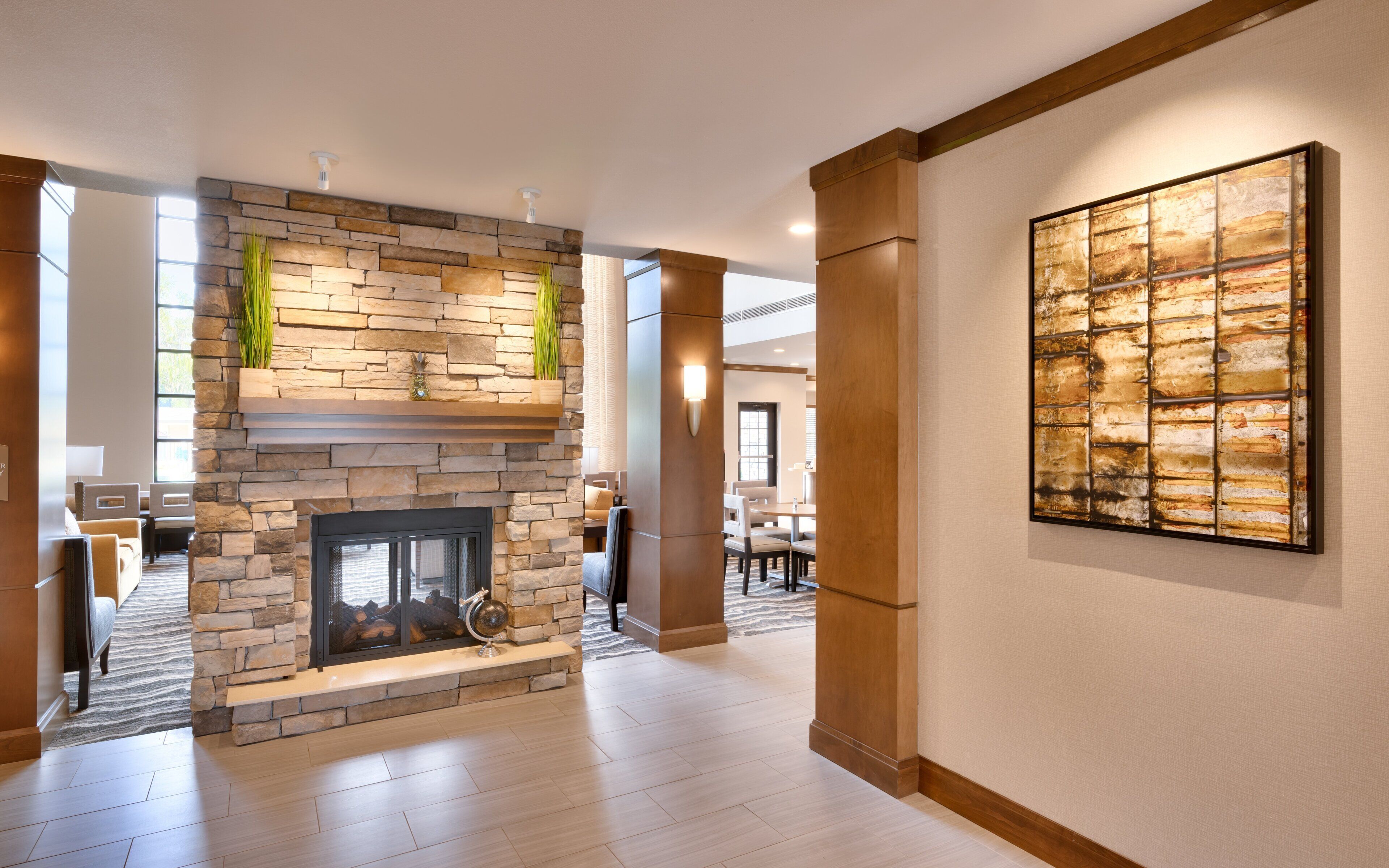 A modern interior with a stone fireplace, a dining area, and a large abstract painting.