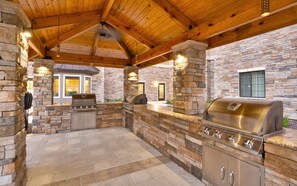An outdoor patio with a stone wall, a grill, and a stone telephone. - Staybridge Suites Gainesville I-75 by IHG (Gainesville)
