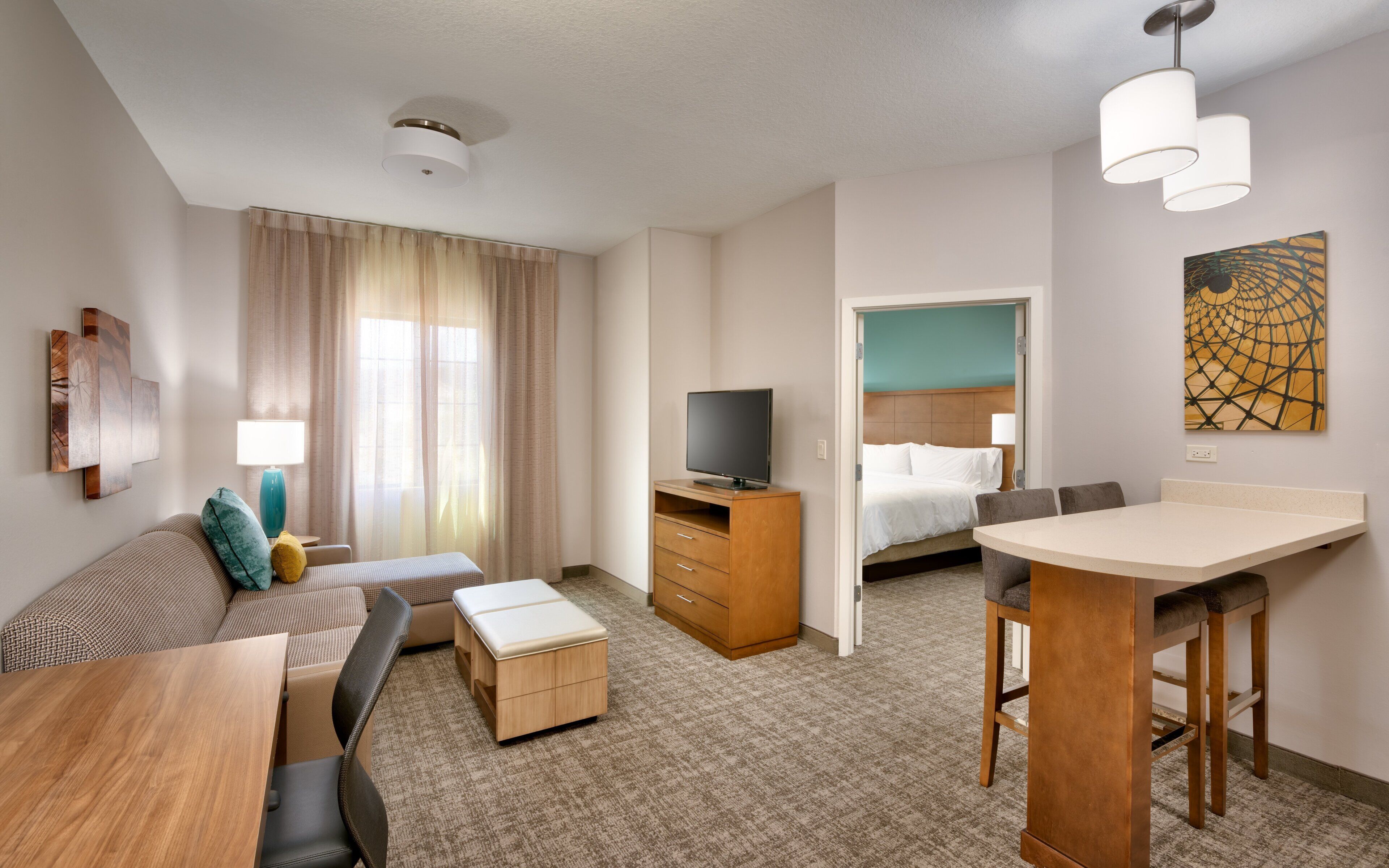 Ein Hotelzimmer mit Sofa, Fernseher, Bett, Schreibtisch und Stuhl.
