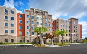 A multi-story hotel with a stone facade, a covered entrance, and a parking lot. - Staybridge Suites Gainesville I-75 by IHG (Gainesville)