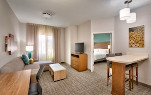 Relax in a cozy seating area with a sofa and bench, featuring a desk, TV, and comfortable bed with a headboard.