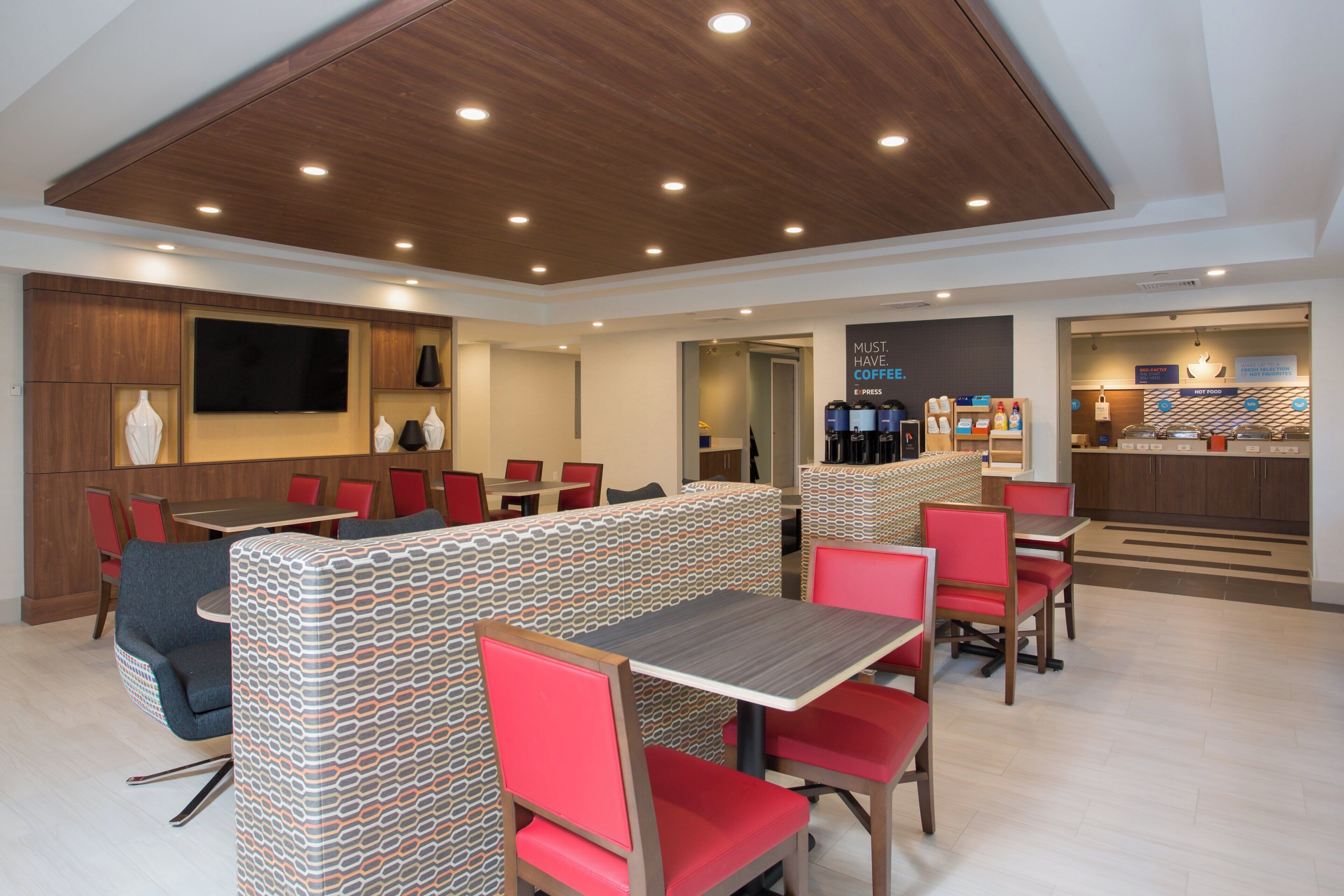 A modern dining area with booths and tables, a coffee station, and a TV screen.