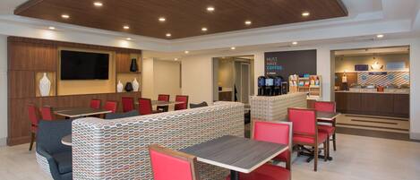 A modern dining area with booths and tables, a coffee station, and a TV screen.