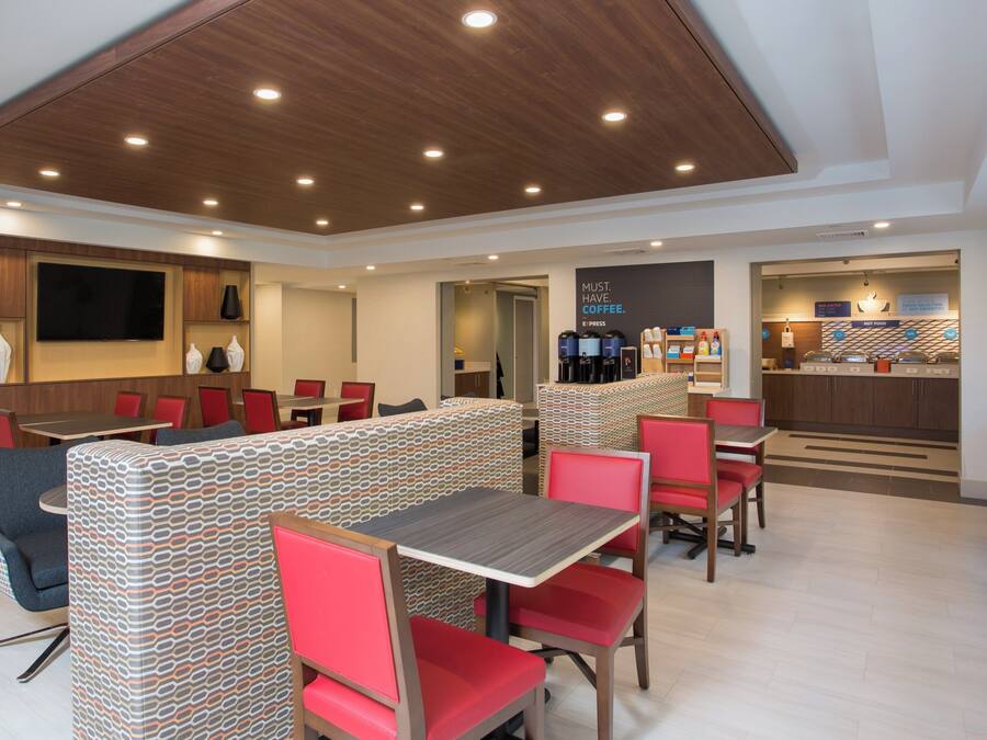 A modern dining area with booths and tables, a coffee station, and a TV screen.