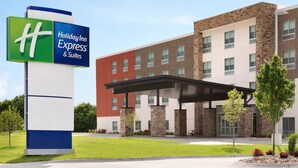 A Holiday Inn Express & Suites building with a modern design, featuring a large sign, a covered entrance, and a landscaped front yard.