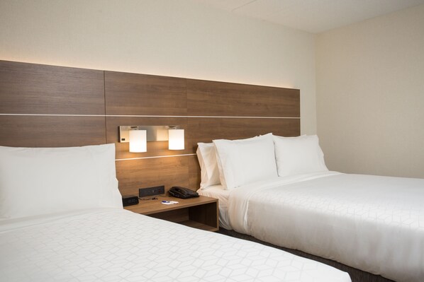 Een hotelkamer met twee bedden, een houten hoofdeinde, bedlampen, een nachtkastje en een telefoon.
