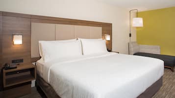 Una habitación de hotel con una cama grande, mesitas de noche, un teléfono y una lámpara.