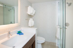 Een moderne badkamer met een douchecabine van glas, een wit wastafelmeubel met spiegel en een toilet.