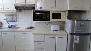 A kitchen with white cabinets, a microwave, a toaster, and a refrigerator.