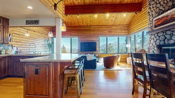 Una cocina amplia con una isla grande, techo de madera y chimenea de piedra.