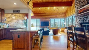 Una cocina amplia con una isla grande, techo de madera y chimenea de piedra.