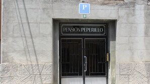 A building entrance with a sign reading "PENSION PEPERILLO" and a parking sign above. - Pensión Peperillo (Graus)