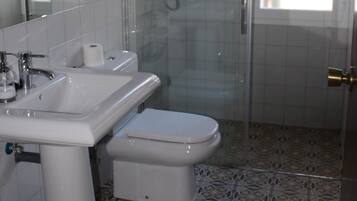 A bathroom with a shower, toilet, sink, and a mirror.
