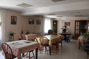 Un comedor con varias mesas y sillas, un reloj en la pared y varias plantas en macetas.