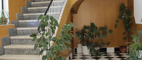 Una escalera con piso a cuadros y plantas en macetas.
