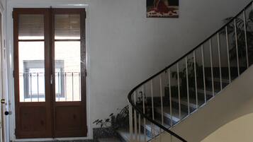 A staircase with a metal railing, a door with a window, and a small plant on the landing.