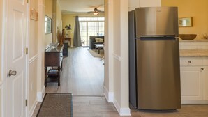 Una cocina con refrigerador de acero inoxidable, armarios de madera y un comedor con mesa y sillas.