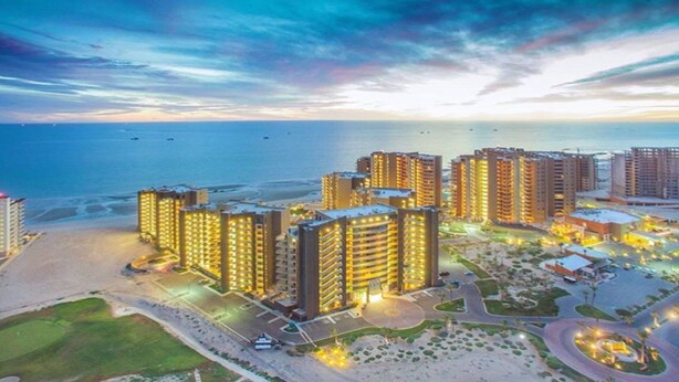 Un hotel de gran altura con varios pisos, ubicación frente a la playa y un estacionamiento bien iluminado.