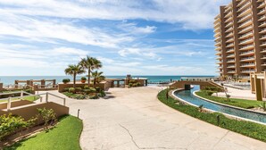 Un resort con piscina, palmeras y vista al océano.