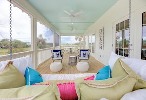 Relax on the porch with a view of the outdoors, featuring two comfortable chairs and a small table.