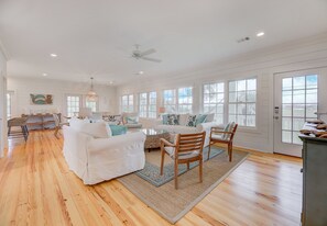 Relax in this spacious living area with a high ceiling, featuring a sofa, chair, and dining table.