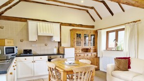 A cozy kitchen with wooden cabinets, a dining table, and a white sofa. - The Dairy , Petersfield -  a barn conversion that sleeps 4 guests  in 1 bedroom (Petersfield)