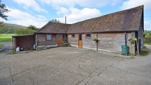 A rustic wooden building with a sloped roof, a front door, and a small porch area. - The Dairy , Petersfield -  a barn conversion that sleeps 4 guests  in 1 bedroom (Petersfield)