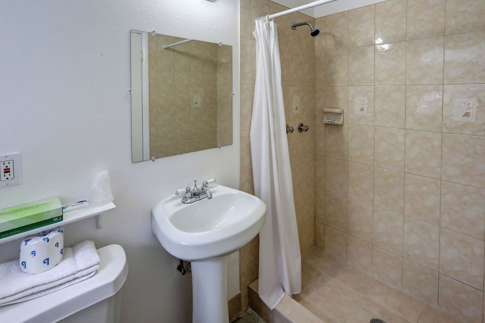 Une salle de bain avec un lavabo, un miroir et une douche.