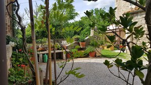 Een tuin met potplanten, een stenen muur en een grindpad.