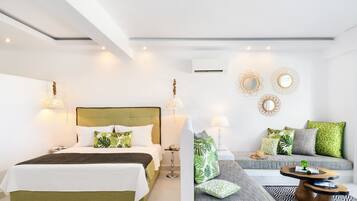 A modern hotel room with a large bed, a sofa, and a small table. There are decorative mirrors and wall sconces.