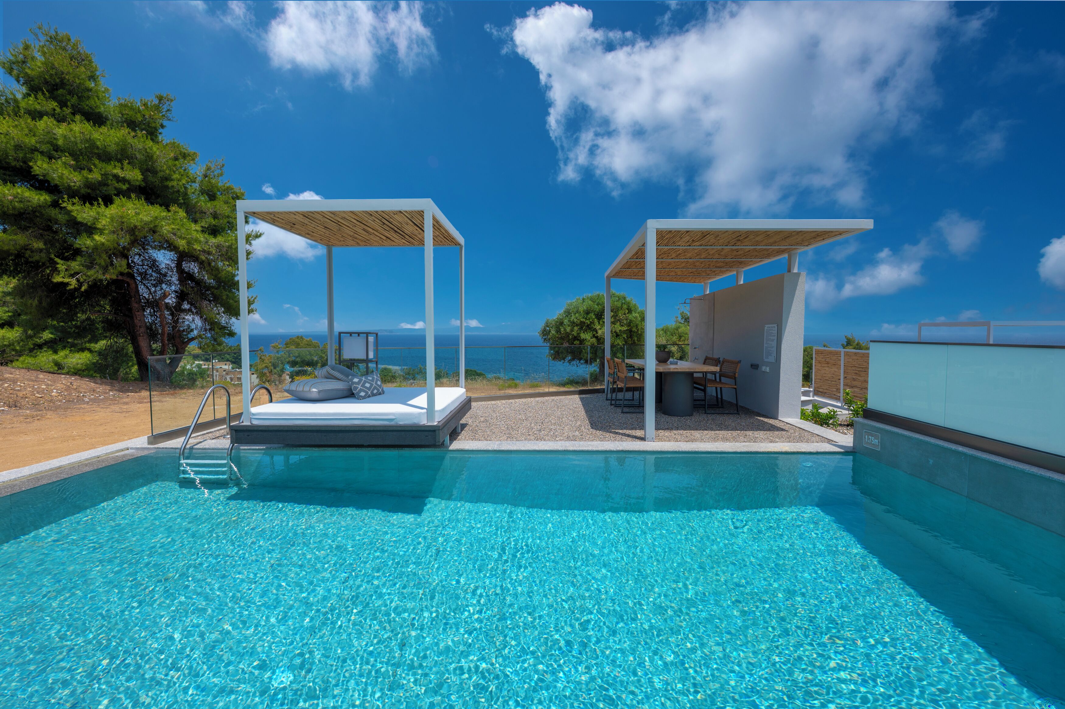 Une piscine d’un bleu éclatant, avec une terrasse en bois, un espace détente et une vue sur la mer.