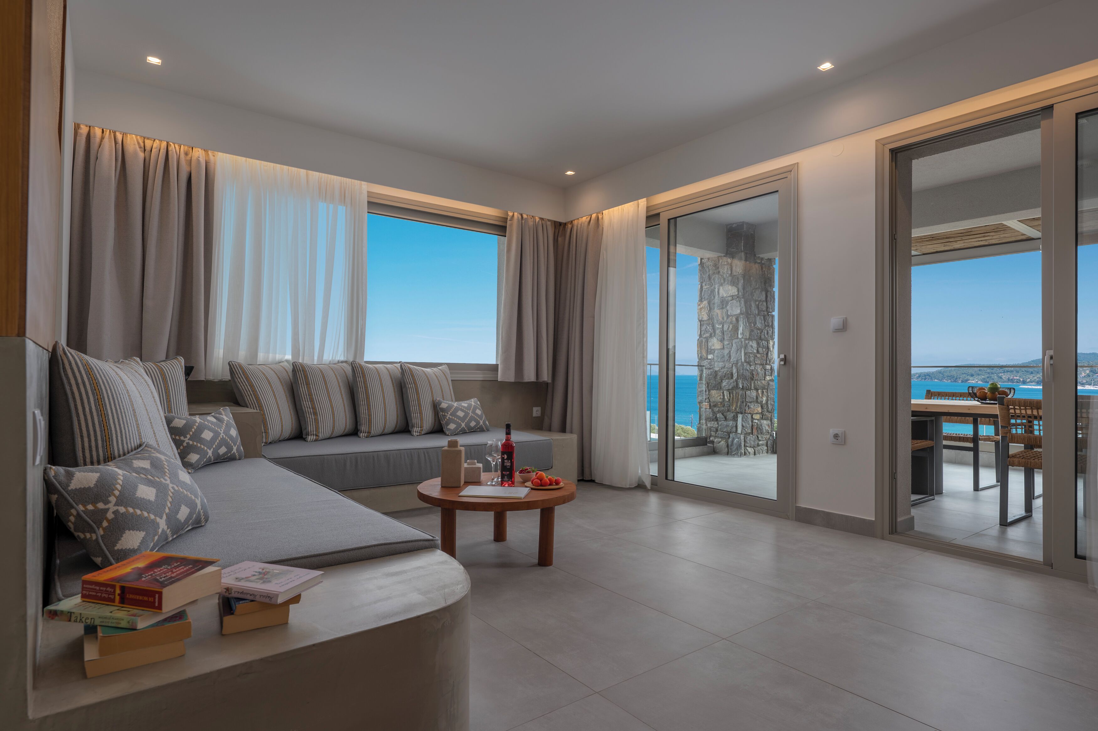 Una sala de estar moderna con un sofá, una mesa de centro y vistas al mar a través de amplios ventanales.
