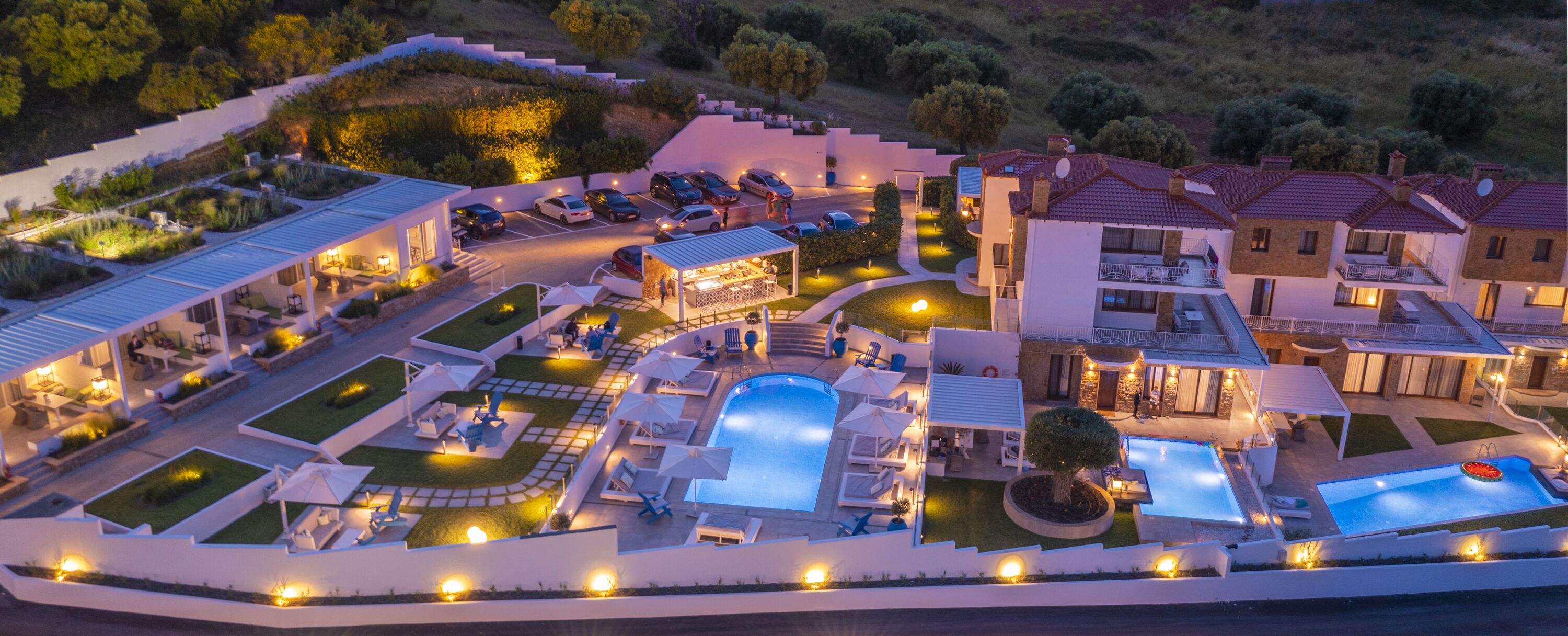 Un resort con varias piscinas, zonas de estar al aire libre y un estacionamiento bien iluminado.