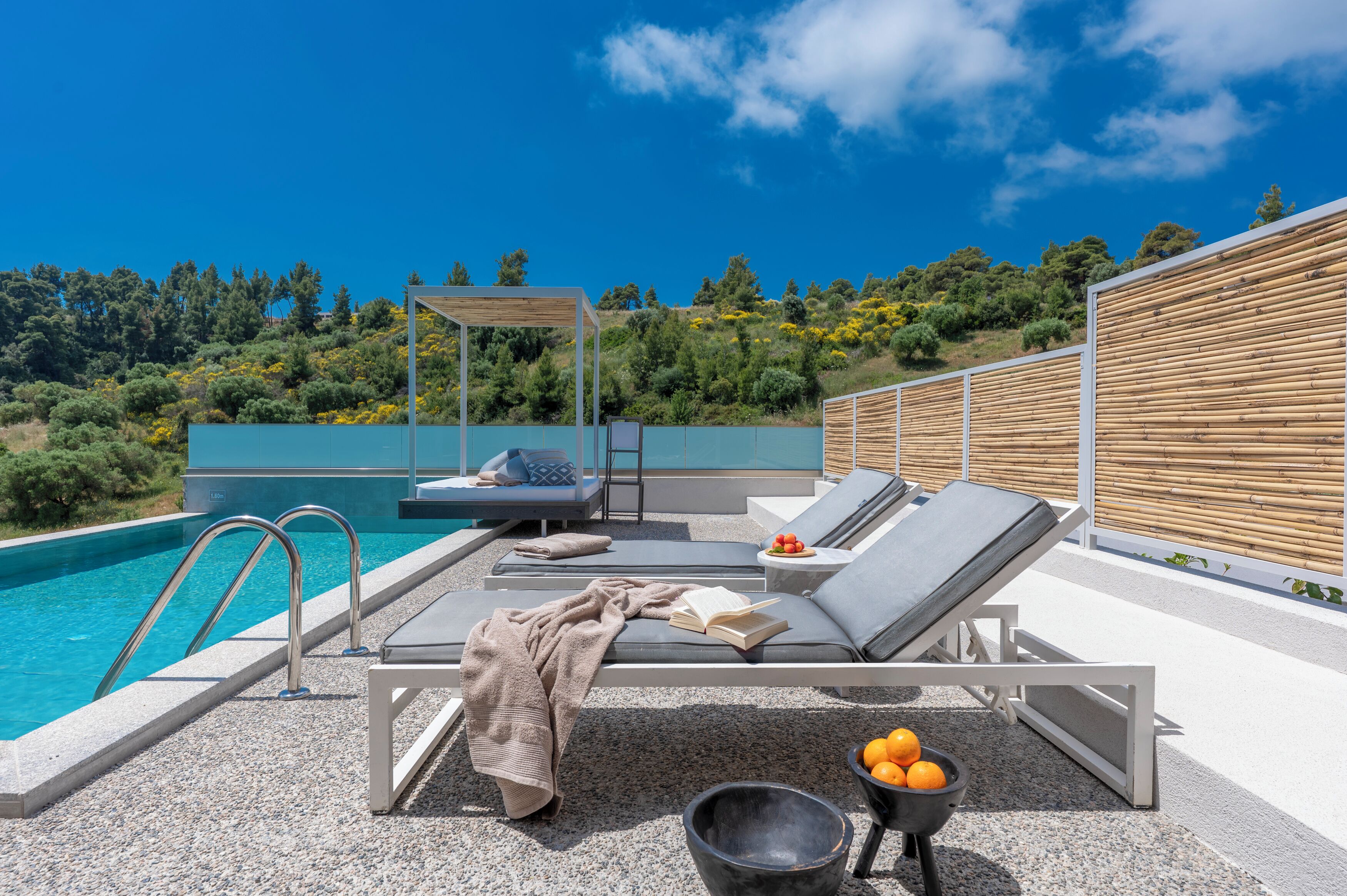 A poolside area with lounge chairs, a small table, and a book.