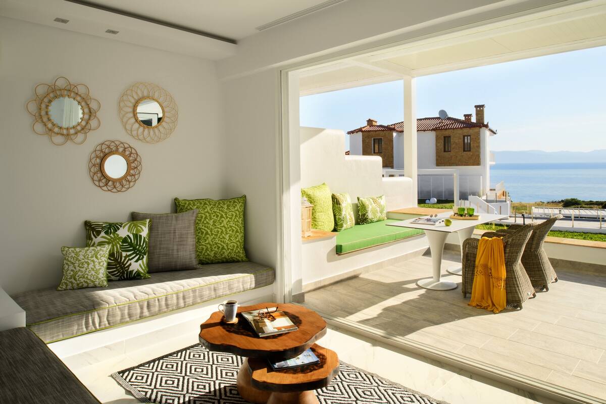 Sala de estar moderna com sofá, mesa de centro e vista para o mar.