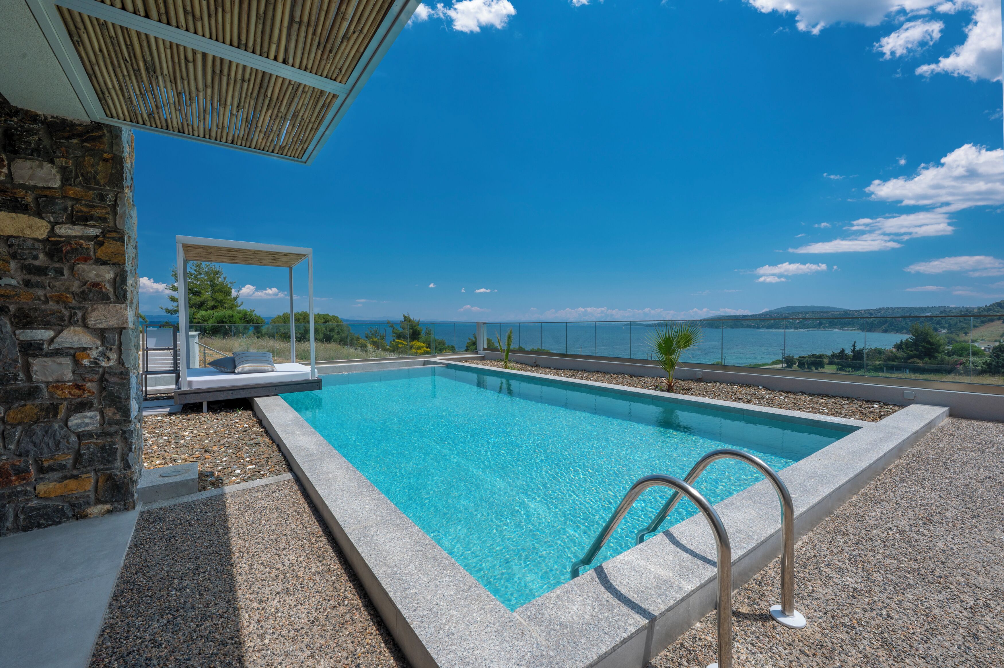 A swimming pool with a clear view of the sea and distant hills.