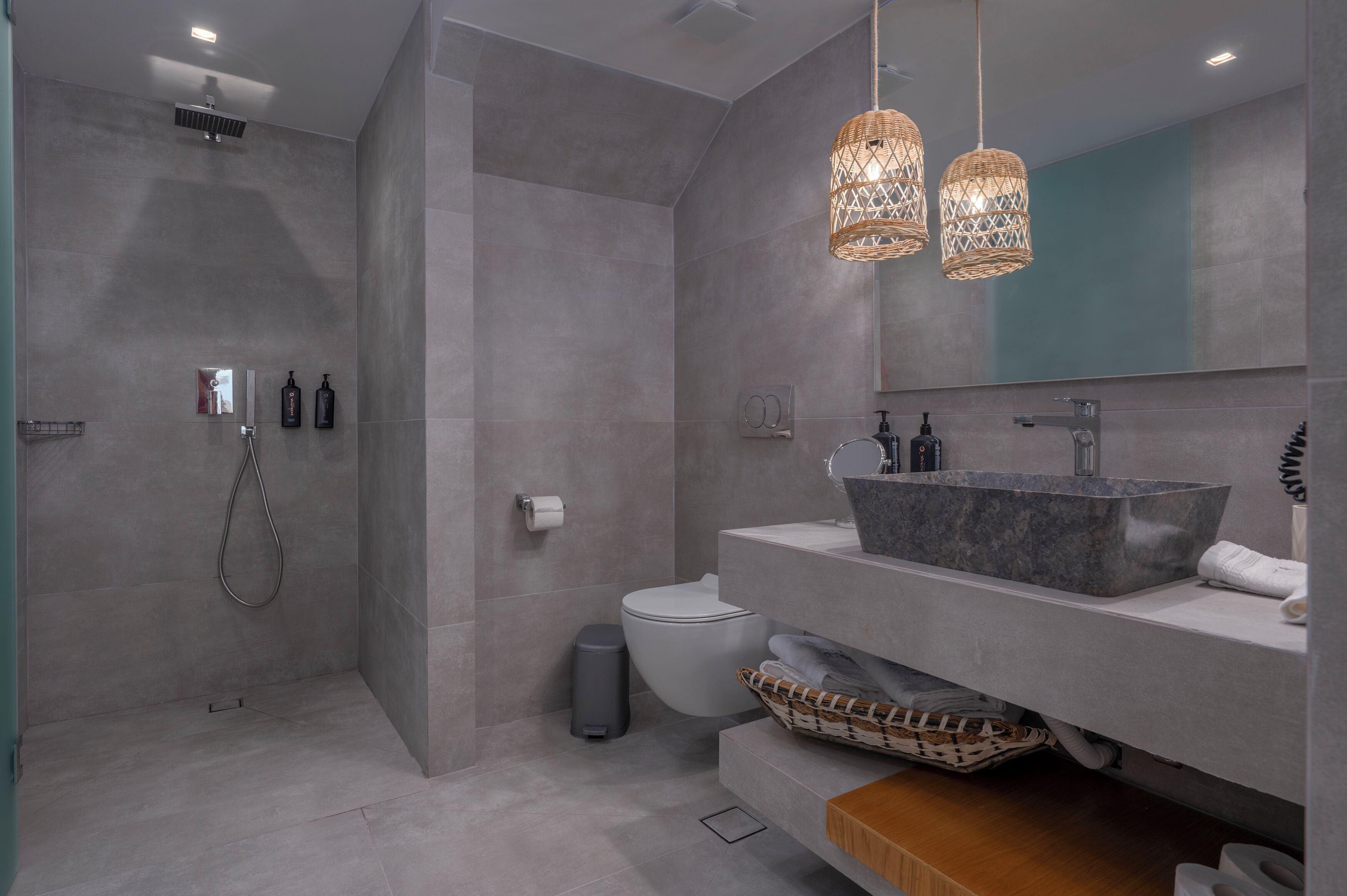 A modern bathroom with a shower, toilet, and vanity with a large sink and mirror.