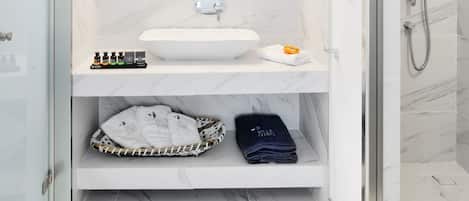 Un baño moderno con un lavamanos blanco, un espejo grande y una ducha con cerramiento de vidrio.