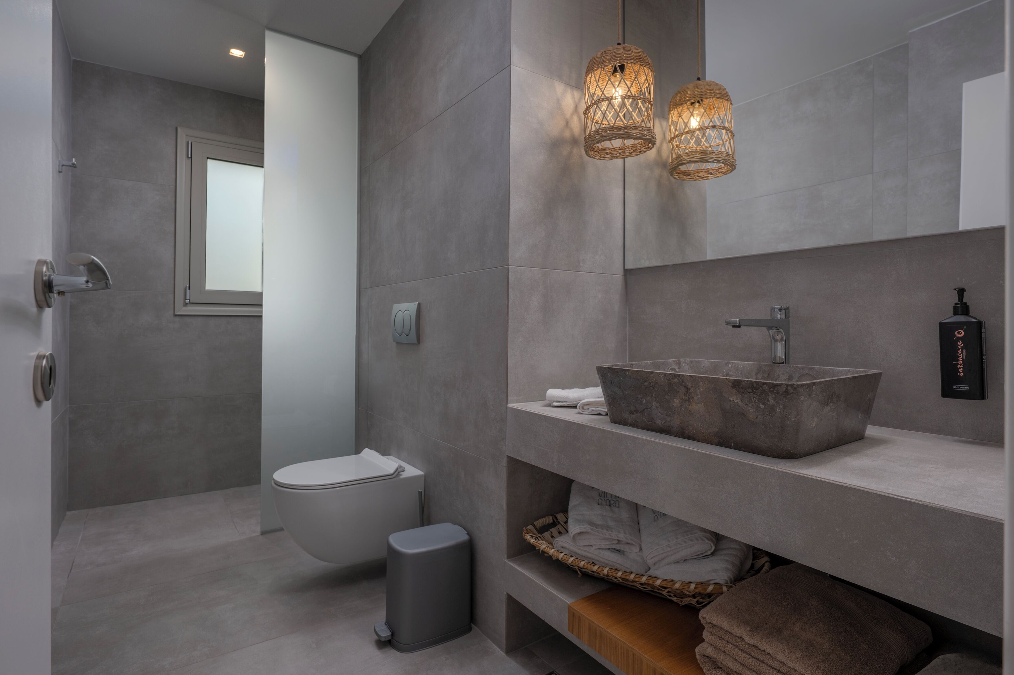A modern bathroom with a large vessel sink, a toilet, and a bidet.
