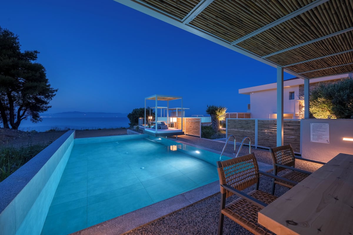 Piscina com área de estar coberta e vista para o mar.