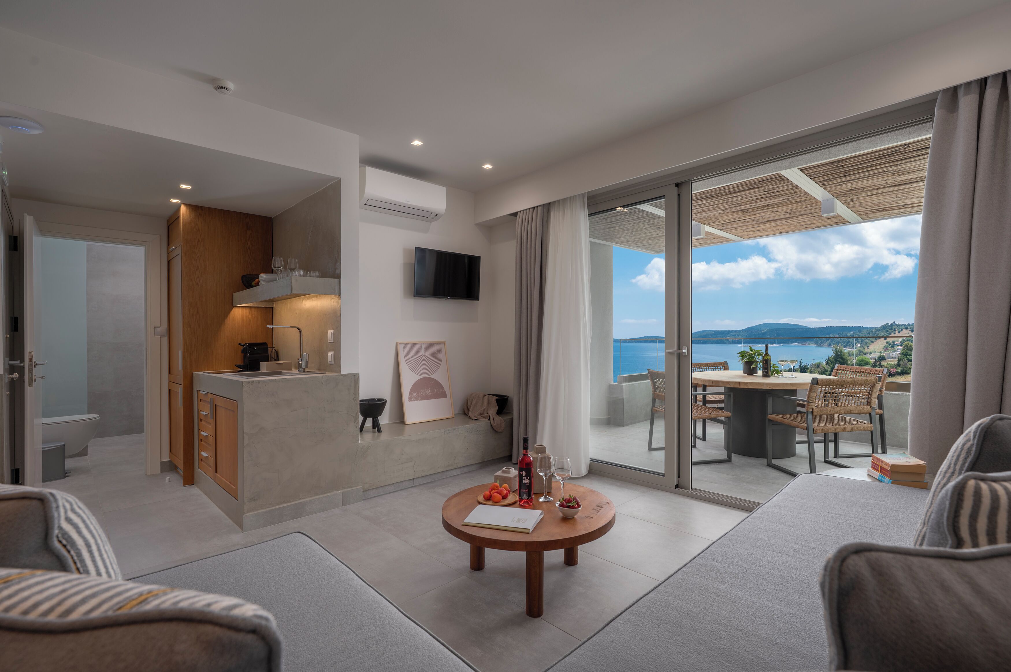 A modern living room with a dining area, a kitchen, and a balcony with a view.