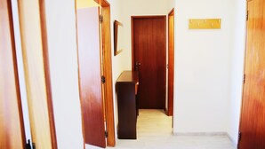 A hallway with wooden doors, a small table, and a wall-mounted light switch. - Algarve Panorama Holidays (Portimão)