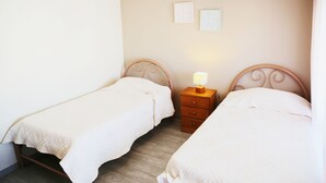 A bedroom with two single beds, a nightstand with a lamp, and a wooden floor. - Algarve Panorama Holidays (Portimão)