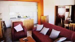 A compact living space with a kitchenette, a red sofa, and a dining area. - Algarve Panorama Holidays (Portimão)